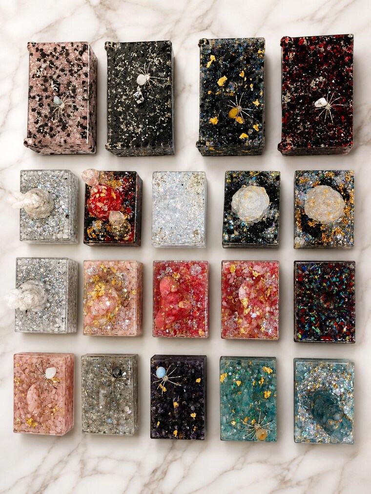 Nineteen finished keepsake boxes laid out together on marble, every one a different colour.