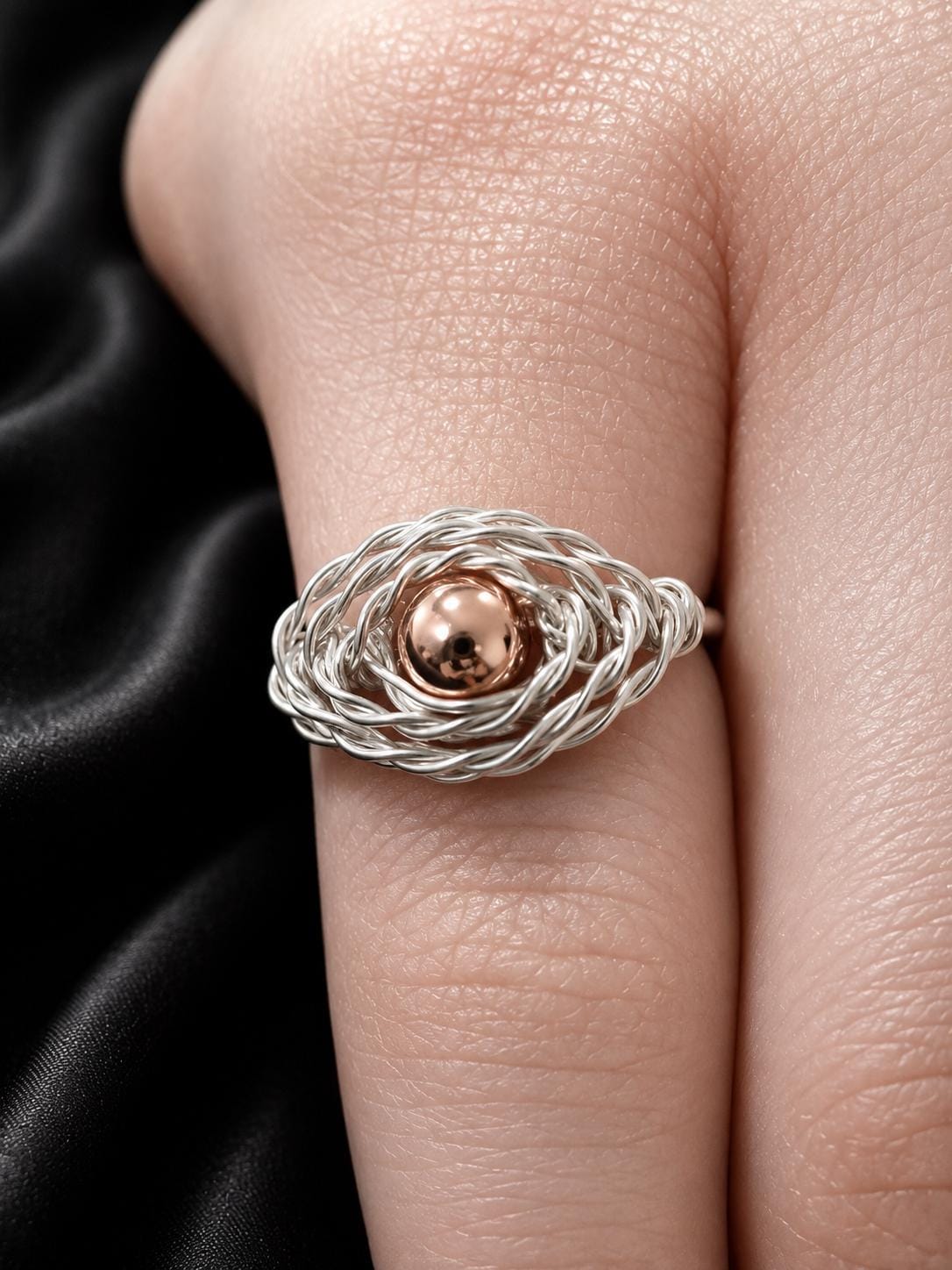 The Nest Ring, fine sterling silver strands woven into a cradle holding a copper sphere.